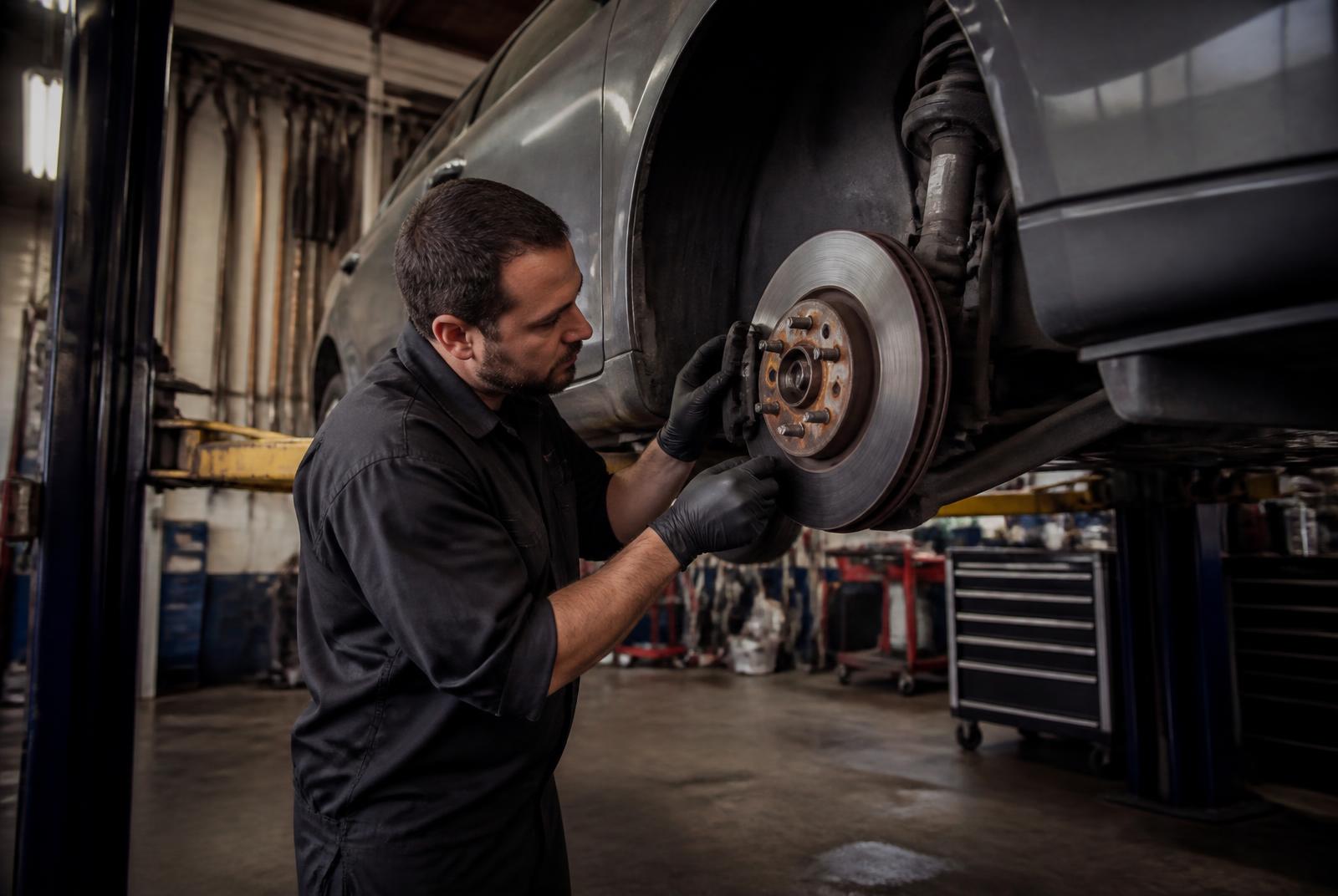 Technician inspecting a brake rotor on a vehicle at Callahan's Muffler & Brake in Pontiac, Michigan